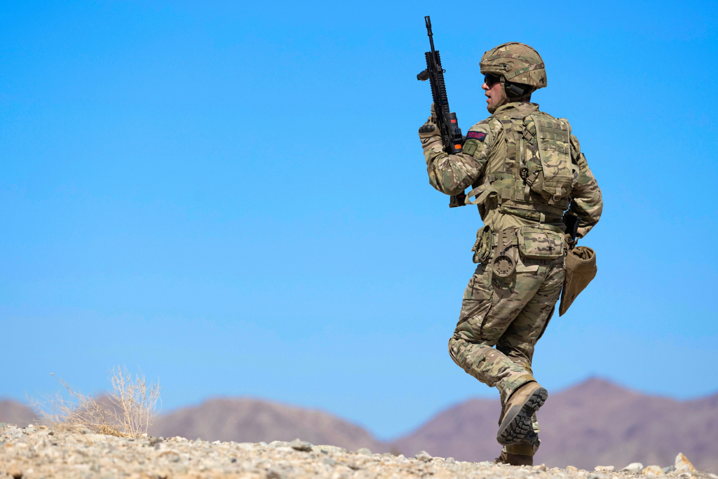 Regular protected by Military Personal Accident Insurance marches across desert.